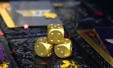 Metal dice on gambling table next to gold coins