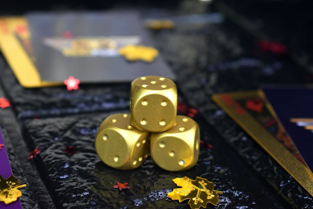 Metal dice on gambling table next to gold coins